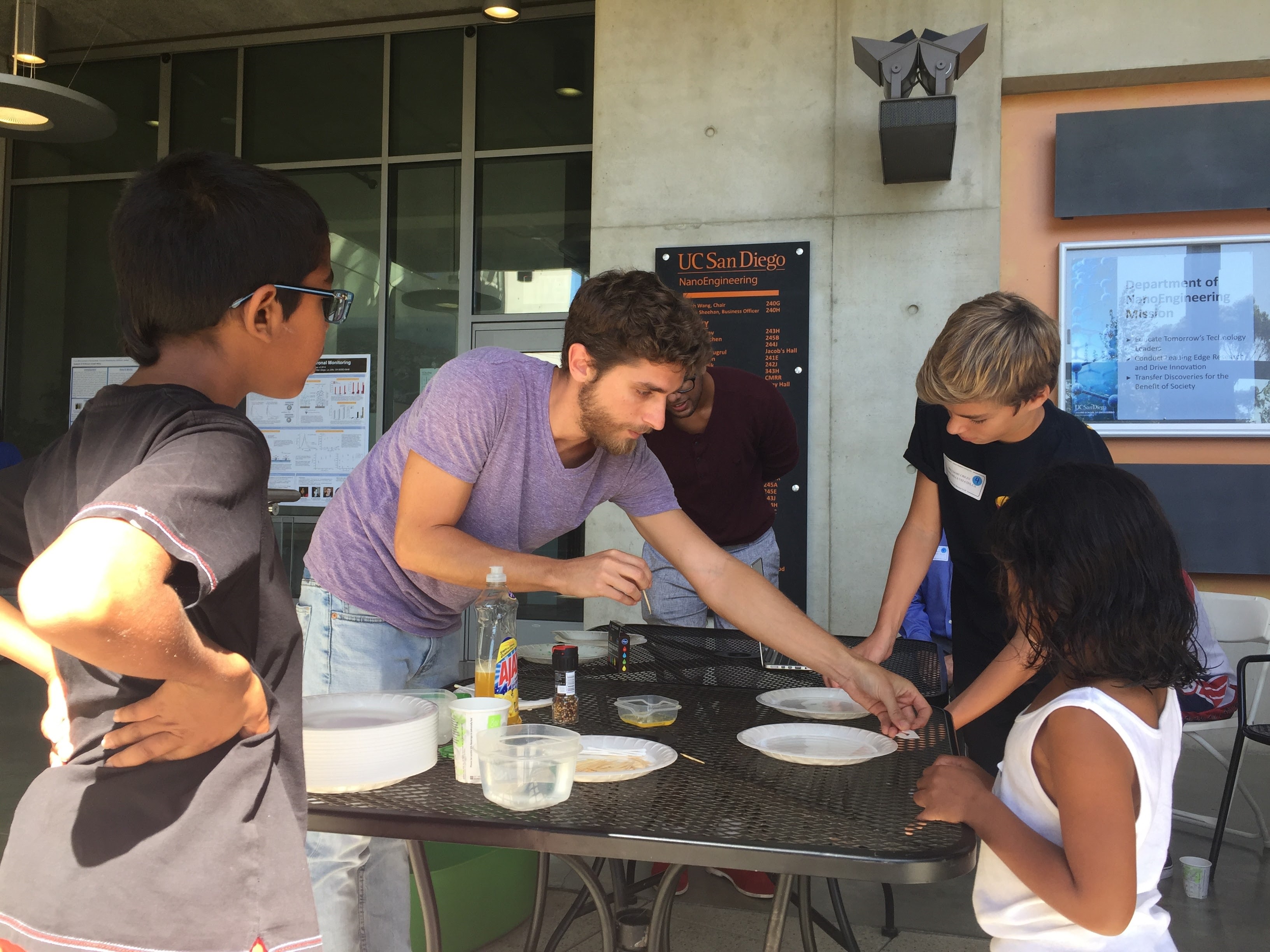 Members of Rangamani’s lab (Chabanon and Ritvik Vasan) teaching middle school students and Rangamani’s children about surface tension, using soap films.